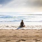 femme qui médite sur une plage face à la mer